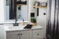 Compact modern bathroom with dual sinks, wood shelves, and black fixtures in Fairbanks Alaska rental