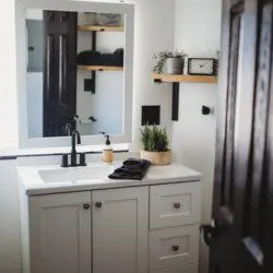 Compact modern bathroom with dual sinks, wood shelves, and black fixtures in Fairbanks Alaska rental
