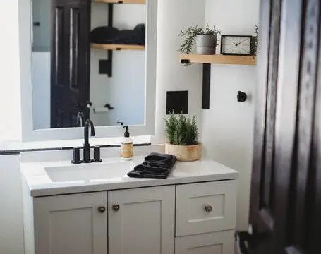 Compact modern bathroom with dual sinks, wood shelves, and black fixtures in Fairbanks Alaska rental