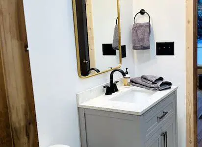 Contemporary bathroom with white vanity, black faucet, and wood accents in a Fairbanks Alaska rental