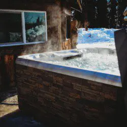 Steaming outdoor hot tub beside rustic wood cabin in snowy Fairbanks Alaska setting