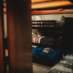 Rustic bunk beds with colorful bedding under exposed wood beams in a Fairbanks Alaska treehouse rental