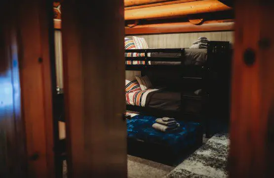 Rustic bunk beds with colorful bedding under exposed wood beams in a Fairbanks Alaska treehouse rental