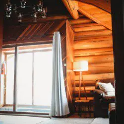 Covered log cabin deck with metal chairs and forest view reflection in Fairbanks Alaska