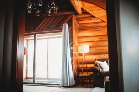 Covered log cabin deck with metal chairs and forest view reflection in Fairbanks Alaska