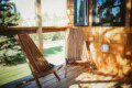 Wooden chairs on a sunny outdoor deck of a Fairbanks Alaska treehouse rental with natural views