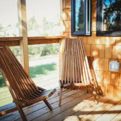 Wooden chairs on a sunny outdoor deck of a Fairbanks Alaska treehouse rental with natural views