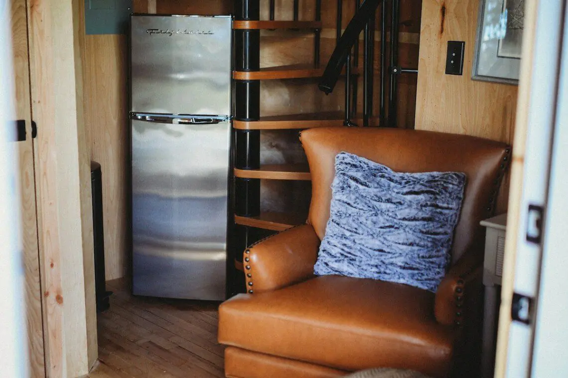 Cozy interior of Fairbanks Alaska treehouse with spiral staircase, leather chair, and loft netting
