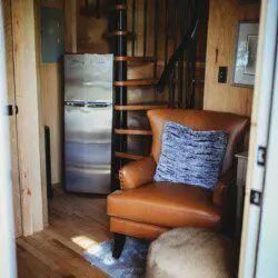 Cozy interior of Fairbanks Alaska treehouse with spiral staircase, leather chair, and loft netting