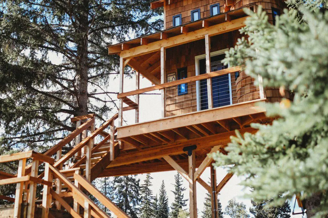 Elevated wooden treehouse with staircase surrounded by trees in Fairbanks, Alaska