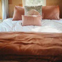 Inviting bed with soft pillows and warm-toned bedding in a wood-paneled Fairbanks Alaska treehouse rental
