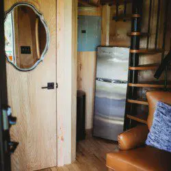 Cozy corner with mini fridge, spiral staircase, and wood interior in a Fairbanks Alaska adventure lodge or treehouse rental