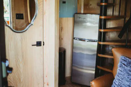 Cozy corner with mini fridge, spiral staircase, and wood interior in a Fairbanks Alaska adventure lodge or treehouse rental
