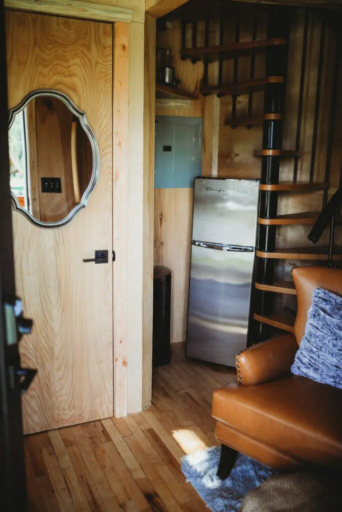 Cozy corner with mini fridge, spiral staircase, and wood interior in a Fairbanks Alaska adventure lodge or treehouse rental