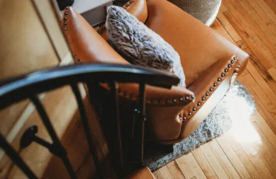 Leather armchair with textured pillows next to spiral staircase in Alaska treehouse rental