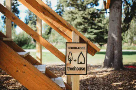 Wood-paneled loft with staircase, large windows, and cozy decor in a Fairbanks Alaska treehouse rental
