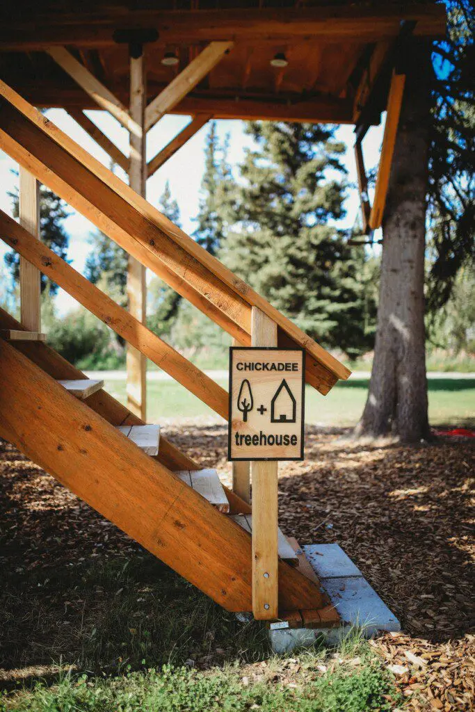 Wood-paneled loft with staircase, large windows, and cozy decor in a Fairbanks Alaska treehouse rental