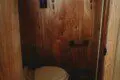 Compact wooden bathroom with toilet in a cozy Fairbanks Alaska adventure lodge or treehouse rental