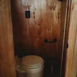 Compact wooden bathroom with toilet in a cozy Fairbanks Alaska adventure lodge or treehouse rental