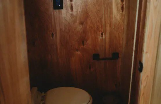 Compact wooden bathroom with toilet in a cozy Fairbanks Alaska adventure lodge or treehouse rental