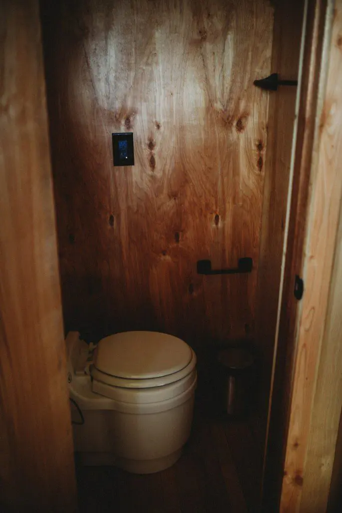 Compact wooden bathroom with toilet in a cozy Fairbanks Alaska adventure lodge or treehouse rental