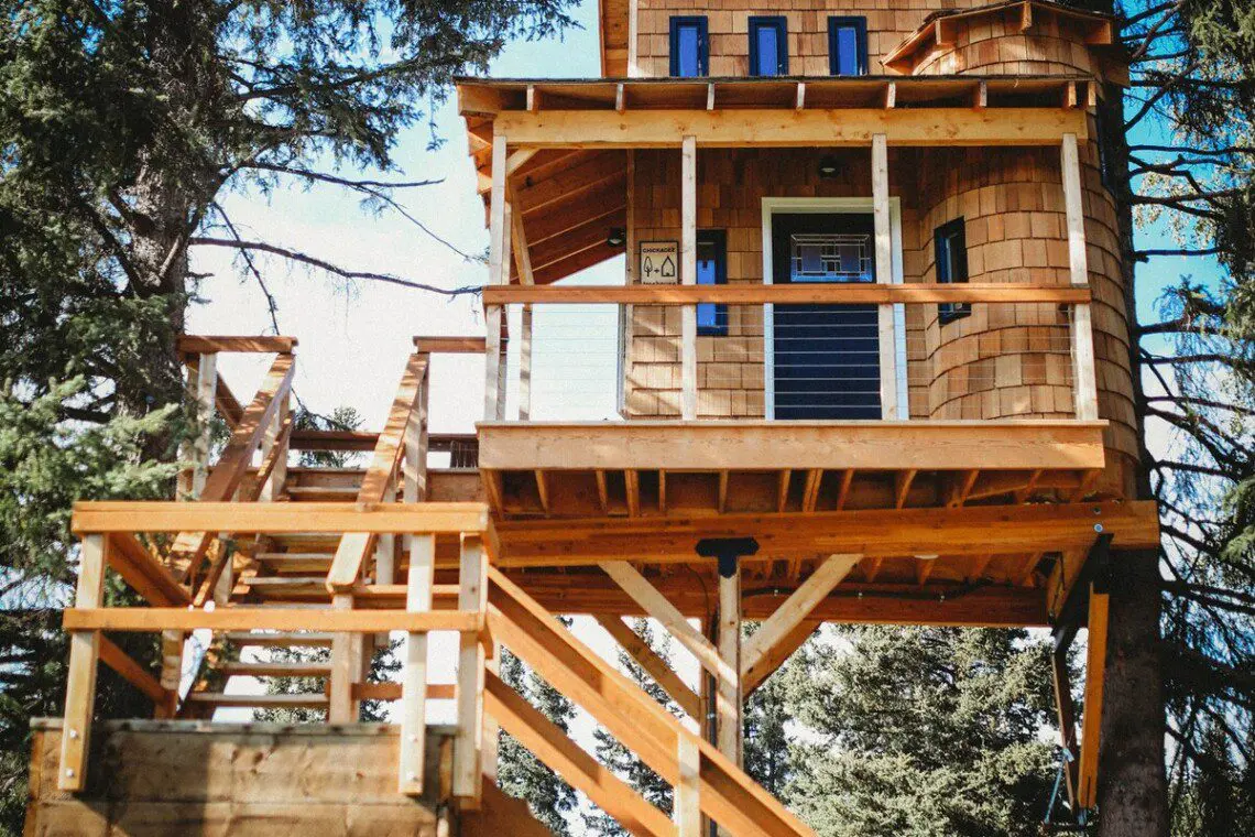 Elevated wooden treehouse with staircase surrounded by trees in Fairbanks, Alaska