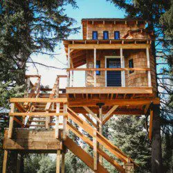Elevated wooden treehouse with staircase surrounded by trees in Fairbanks, Alaska