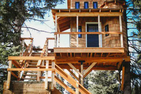 Elevated wooden treehouse with staircase surrounded by trees in Fairbanks, Alaska