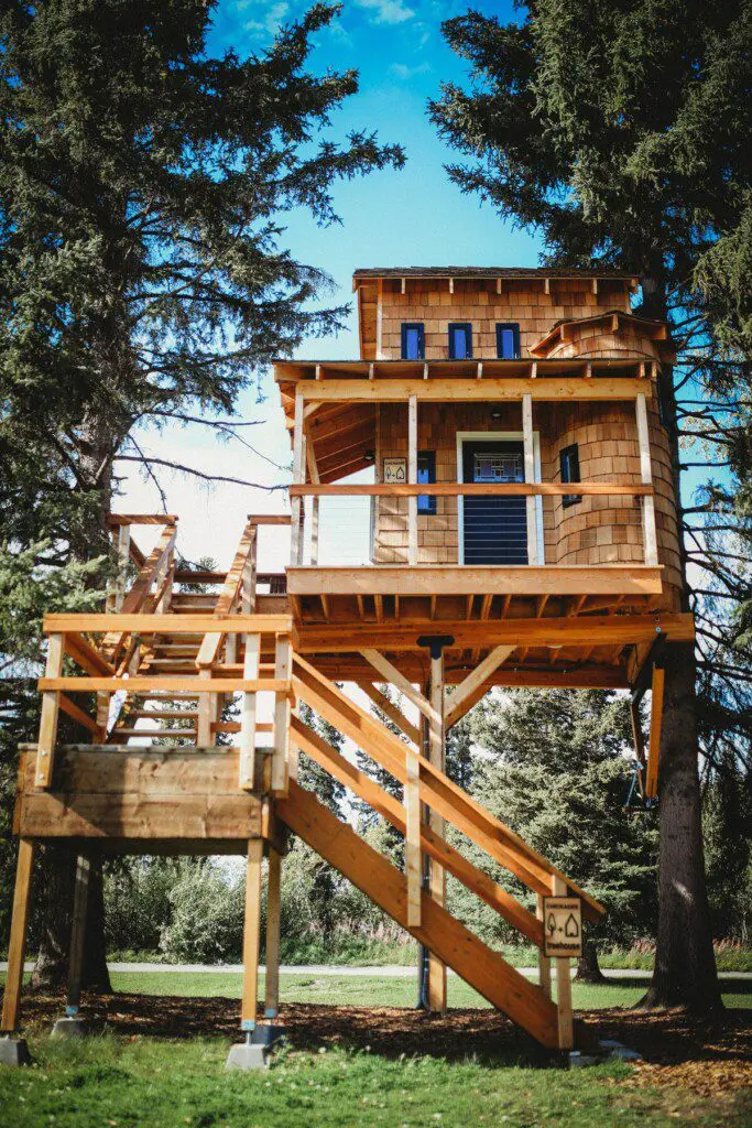 Elevated wooden treehouse with staircase surrounded by trees in Fairbanks, Alaska