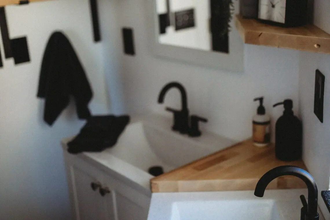 Modern double-sink bathroom with black fixtures and wood shelving in a Fairbanks Alaska treehouse rental.