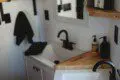 Modern double-sink bathroom with black fixtures and wood shelving in a Fairbanks Alaska treehouse rental.