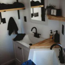 Modern double-sink bathroom with black fixtures and wood shelving in a Fairbanks Alaska treehouse rental.