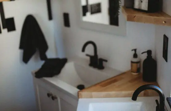 Modern double-sink bathroom with black fixtures and wood shelving in a Fairbanks Alaska treehouse rental.