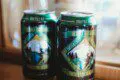 Two cans of local craft beer on a wooden counter inside a cozy Alaska adventure lodge near Fairbanks