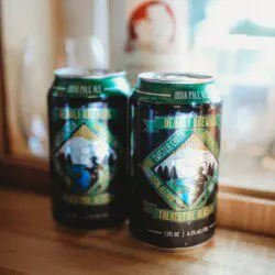 Two cans of local craft beer on a wooden counter inside a cozy Alaska adventure lodge near Fairbanks