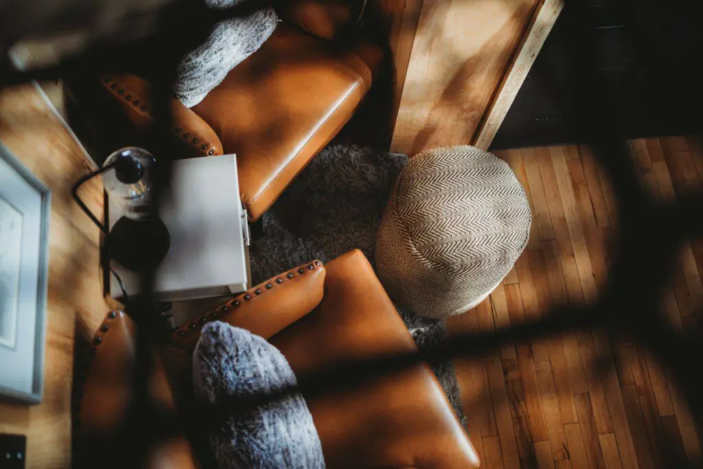 Top view of a sunlit lounge area with leather chairs and rustic decor in a Fairbanks Alaska treehouse rental