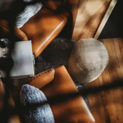 Top view of a sunlit lounge area with leather chairs and rustic decor in a Fairbanks Alaska treehouse rental