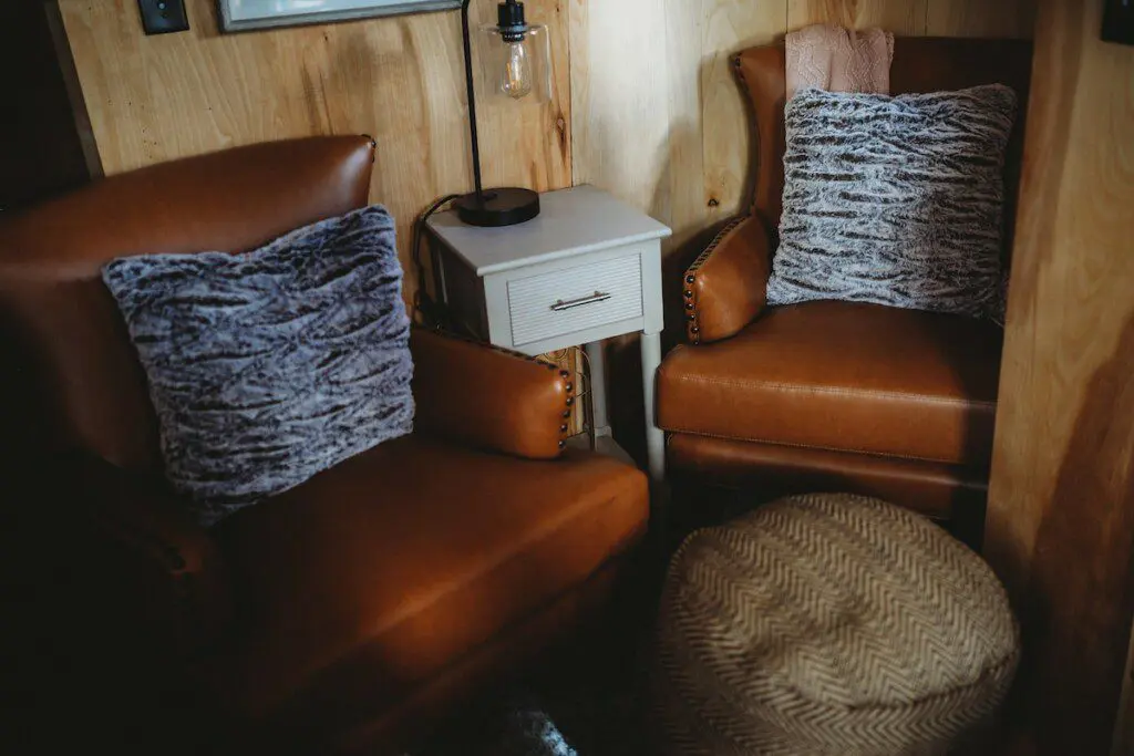 Leather armchairs with soft pillows and a side table in a cozy treehouse rental in Fairbanks, Alaska  Caption: