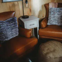 Leather armchairs with soft pillows and a side table in a cozy treehouse rental in Fairbanks, Alaska  Caption: