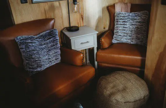 Leather armchairs with soft pillows and a side table in a cozy treehouse rental in Fairbanks, Alaska  Caption: