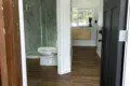 Open black door revealing a clean bathroom with glass shower and wood-look tile flooring in a Fairbanks rental