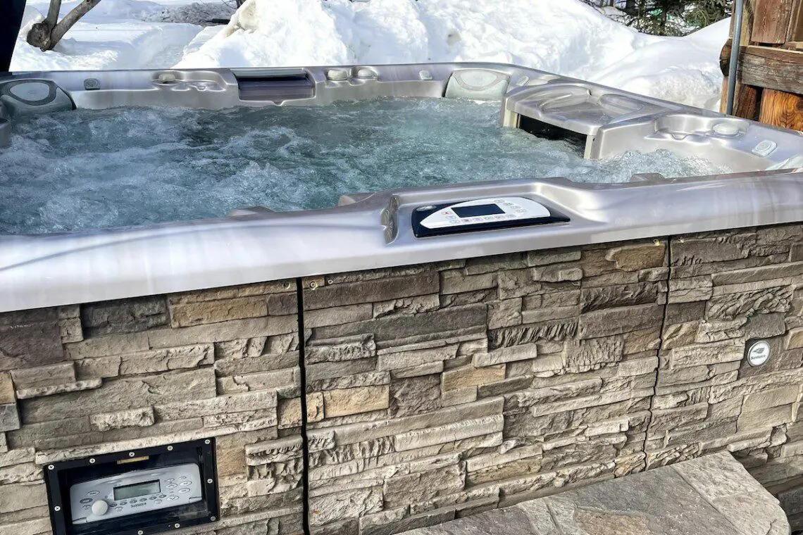 Bubbling outdoor hot tub with stone siding in a snowy Fairbanks Alaska forest setting