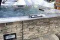 Bubbling outdoor hot tub with stone siding in a snowy Fairbanks Alaska forest setting