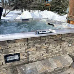 Bubbling outdoor hot tub with stone siding in a snowy Fairbanks Alaska forest setting