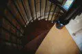 Top-down view of a wooden spiral staircase with black railing in a cozy Fairbanks Alaska treehouse rental