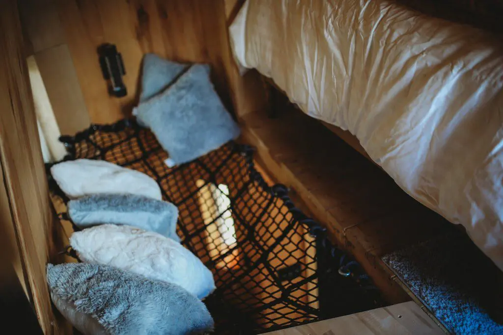 Creative sleeping nook with pillows and netting in a rustic Fairbanks Alaska treehouse rental or adventure lodge