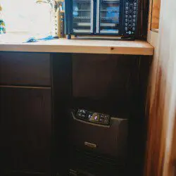 Retro stainless steel refrigerator beside a spiral staircase in a rustic Fairbanks Alaska treehouse rental