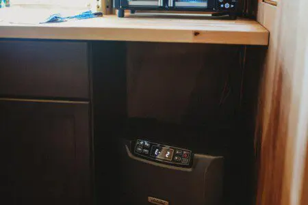 Retro stainless steel refrigerator beside a spiral staircase in a rustic Fairbanks Alaska treehouse rental