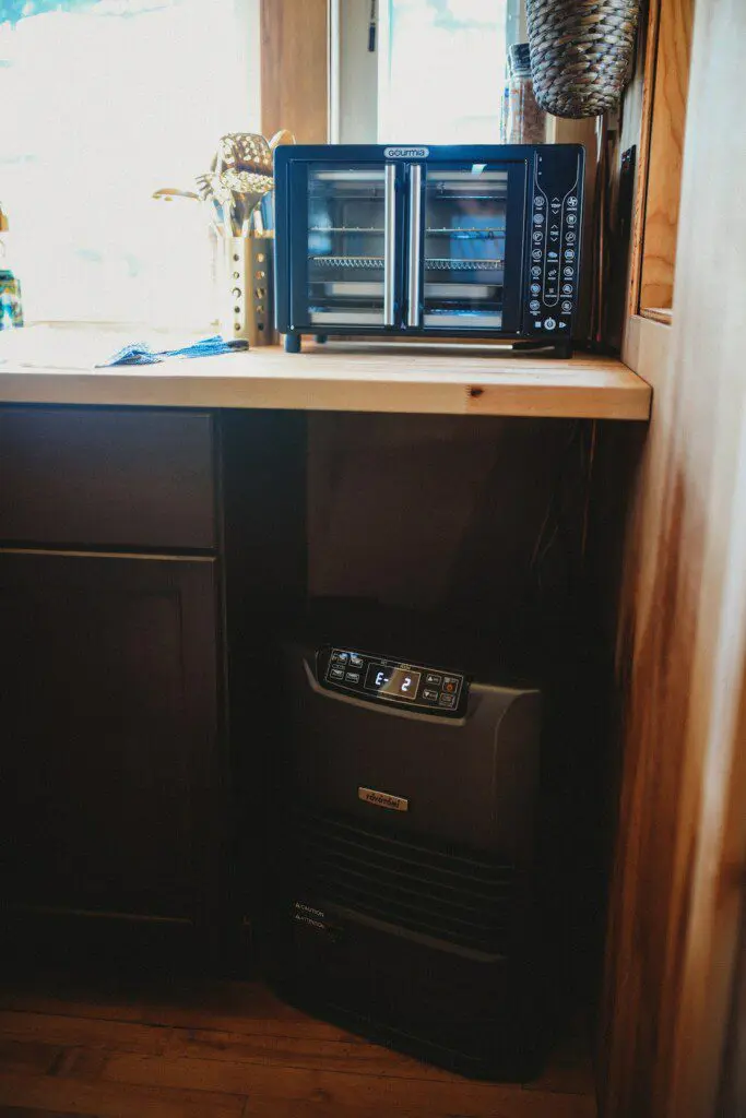 Retro stainless steel refrigerator beside a spiral staircase in a rustic Fairbanks Alaska treehouse rental