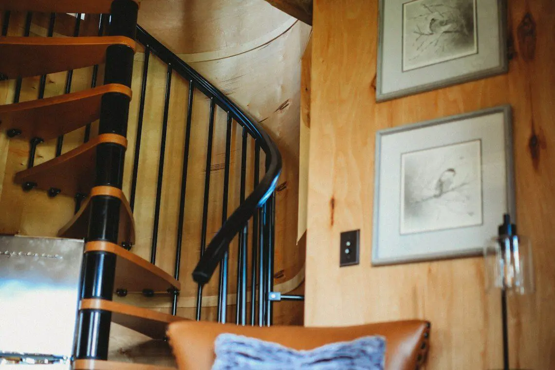 Wood-paneled interior with spiral staircase, leather chair, and cozy decor in a Fairbanks Alaska treehouse rental